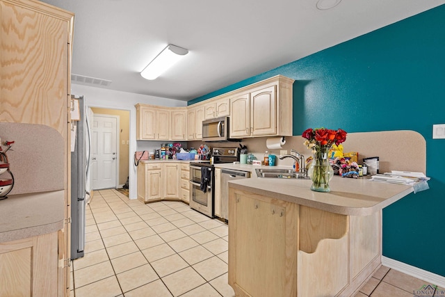 kitchen with light tile patterned flooring, appliances with stainless steel finishes, light brown cabinets, and sink