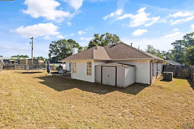 back of house featuring a lawn, cooling unit, a shed, and a trampoline