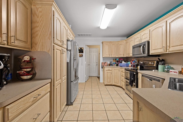 kitchen with appliances with stainless steel finishes, sink, light brown cabinetry, and light tile patterned flooring