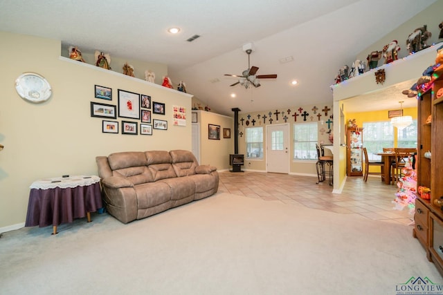 living room with vaulted ceiling, a wood stove, ceiling fan, and light tile patterned flooring