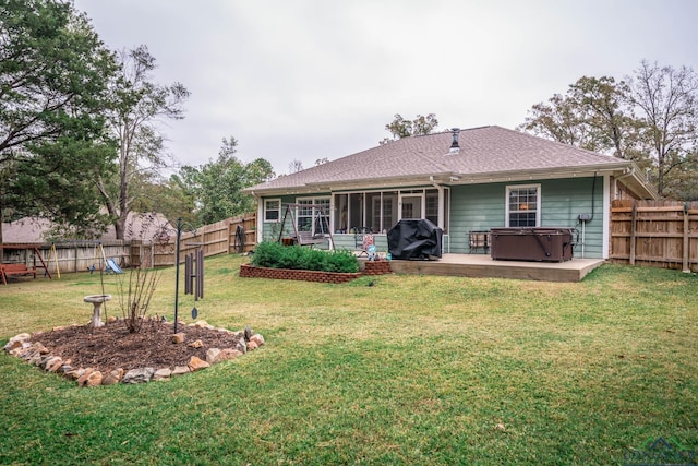 rear view of property featuring a sunroom, a patio area, a yard, and a hot tub