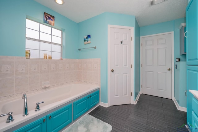 bathroom with a tub, tile patterned flooring, vanity, and a textured ceiling