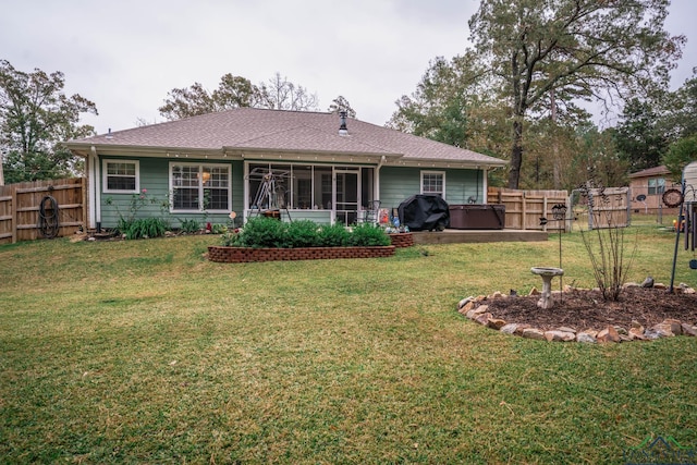 rear view of house featuring a lawn and a hot tub