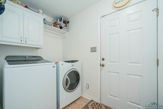 clothes washing area with cabinets, light tile patterned floors, a textured ceiling, and washing machine and clothes dryer