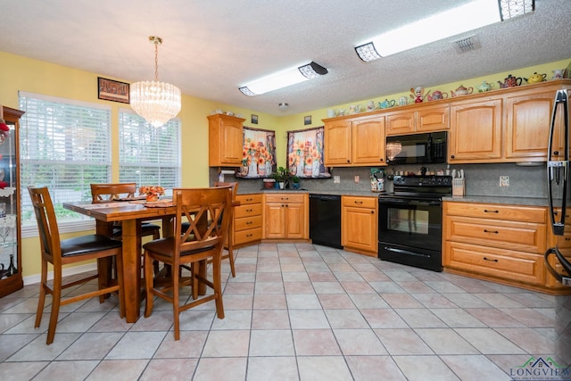 kitchen with black appliances, decorative light fixtures, a skylight, decorative backsplash, and a notable chandelier