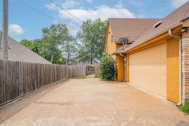 2120 Page Rd, Longview, TX 75601 - view of side of home with driveway, a shingled roof, an attached garage, and stucco siding