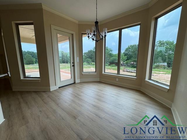 unfurnished dining area with light hardwood / wood-style flooring, ornamental molding, and a notable chandelier