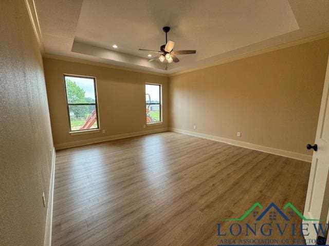 unfurnished room featuring a raised ceiling, ceiling fan, crown molding, and hardwood / wood-style flooring