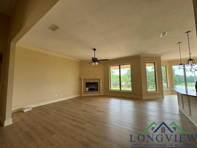 unfurnished living room with ceiling fan, crown molding, a textured ceiling, and hardwood / wood-style flooring