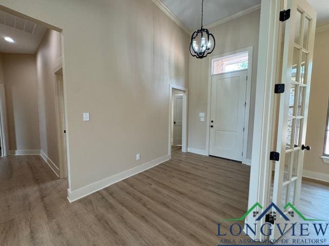 entryway with wood-type flooring and crown molding