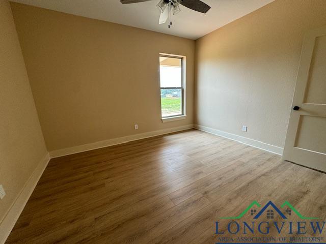 empty room with hardwood / wood-style floors and ceiling fan