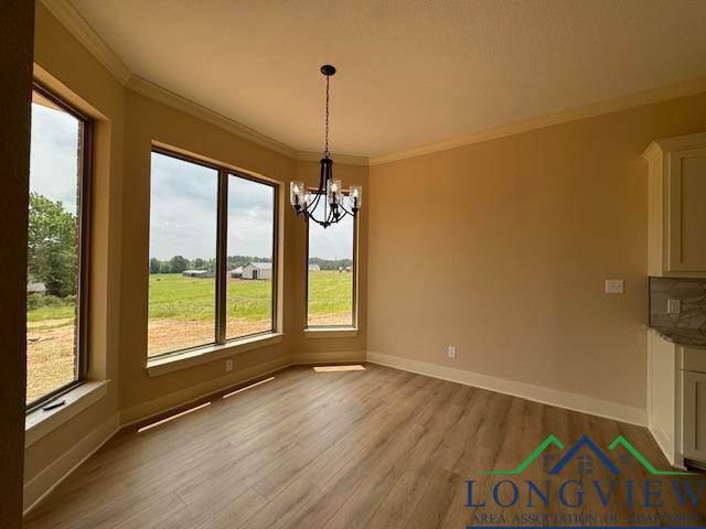 unfurnished dining area featuring ornamental molding, a chandelier, and light wood-type flooring