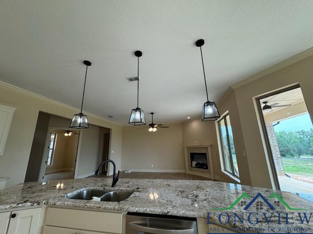 kitchen featuring light stone countertops, sink, pendant lighting, dishwasher, and white cabinets