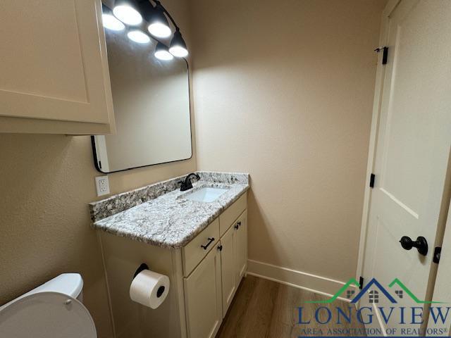 bathroom featuring hardwood / wood-style floors, vanity, and toilet