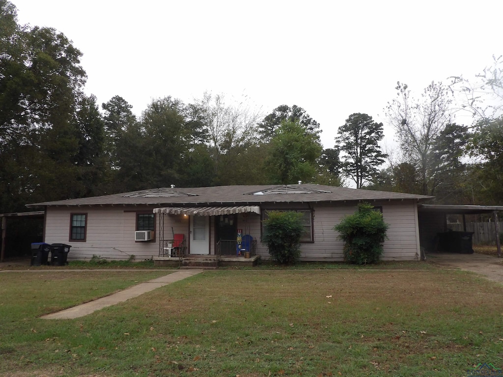 ranch-style home featuring a carport, cooling unit, and a front yard