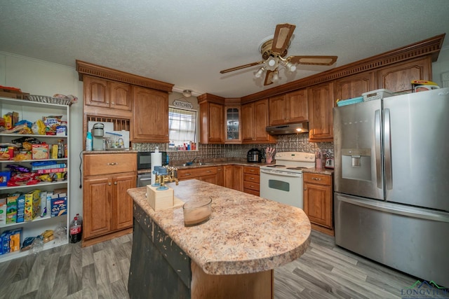 10816 Fm 2685, Gladewater, TX 75647 - kitchen with stainless steel fridge, white range with electric cooktop, under cabinet range hood, a ceiling fan, and backsplash