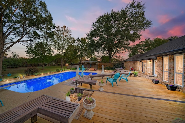 pool at dusk featuring a deck