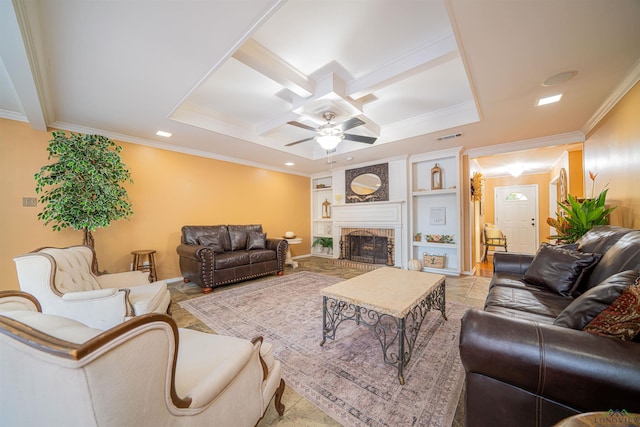 tiled living room with built in shelves, ceiling fan, crown molding, and a brick fireplace