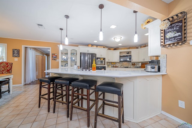 kitchen with kitchen peninsula, a breakfast bar, stainless steel appliances, white cabinets, and light tile patterned flooring