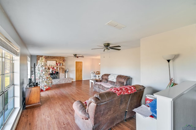 living room featuring a brick fireplace, hardwood / wood-style floors, and ceiling fan