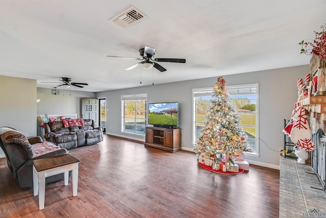 living room featuring a brick fireplace, a wealth of natural light, dark wood-type flooring, and ceiling fan