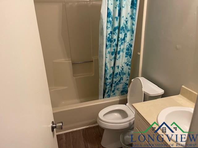 full bathroom with hardwood / wood-style floors, vanity, toilet, and shower / bath combo with shower curtain