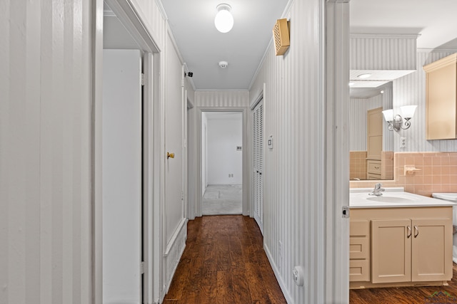 corridor featuring crown molding, sink, and dark wood-type flooring