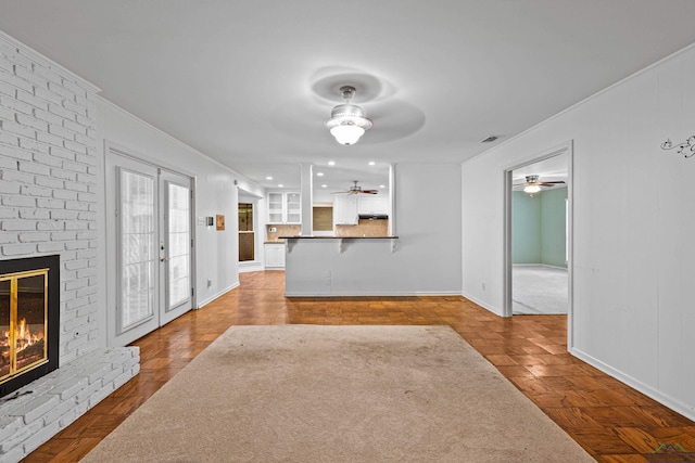 unfurnished living room featuring french doors, parquet flooring, and a brick fireplace