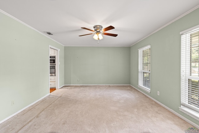 carpeted spare room with a wealth of natural light, ornamental molding, and ceiling fan