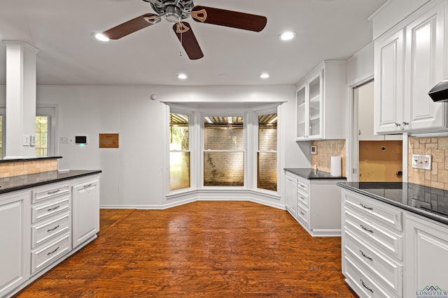 kitchen featuring backsplash, dark wood-type flooring, white cabinets, ceiling fan, and dark stone countertops