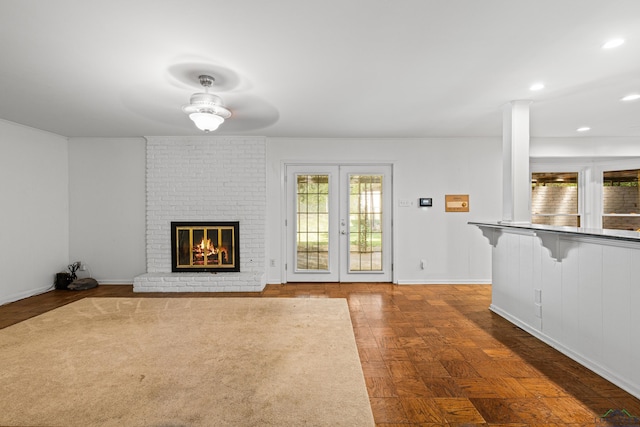 unfurnished living room with parquet flooring, french doors, and a brick fireplace