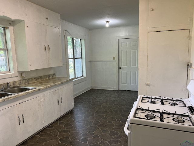 710 Aurel Ave, Longview, TX 75602 - kitchen with white gas range oven, light countertops, crown molding, white cabinets, and dark stone finish flooring