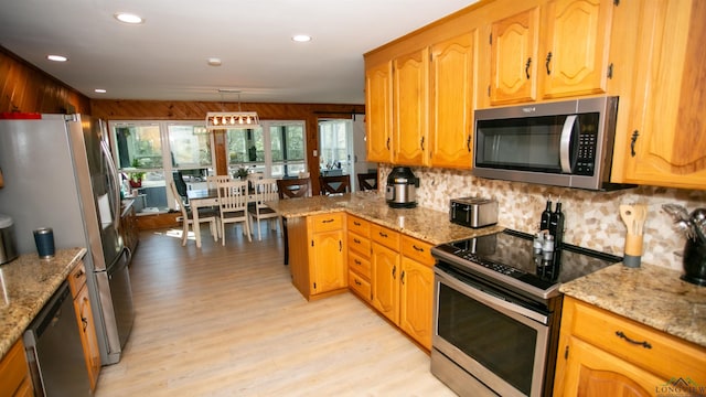 kitchen featuring tasteful backsplash, recessed lighting, light wood finished floors, light stone countertops, and appliances with stainless steel finishes