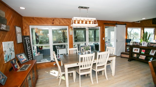 dining area featuring light wood-type flooring, wood walls, and recessed lighting