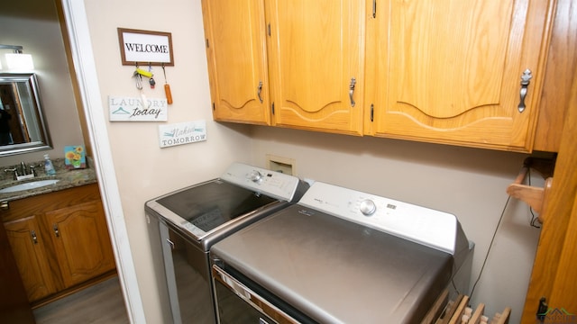 laundry area featuring cabinet space, a sink, independent washer and dryer, and wood finished floors