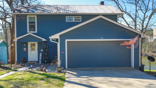 view of front of home featuring driveway, an attached garage, and metal roof