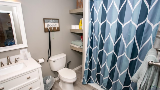bathroom featuring baseboards, toilet, wood finished floors, vanity, and a shower with curtain