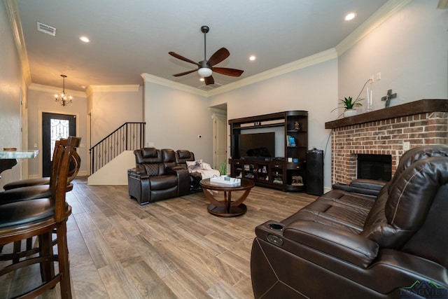 living room with a fireplace, crown molding, hardwood / wood-style floors, and ceiling fan with notable chandelier