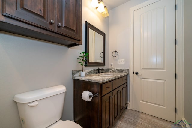 bathroom with hardwood / wood-style floors, vanity, and toilet