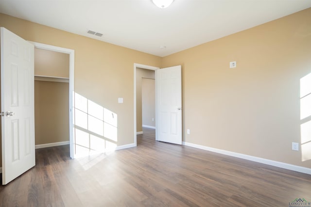 unfurnished bedroom featuring dark wood-type flooring, a spacious closet, and a closet