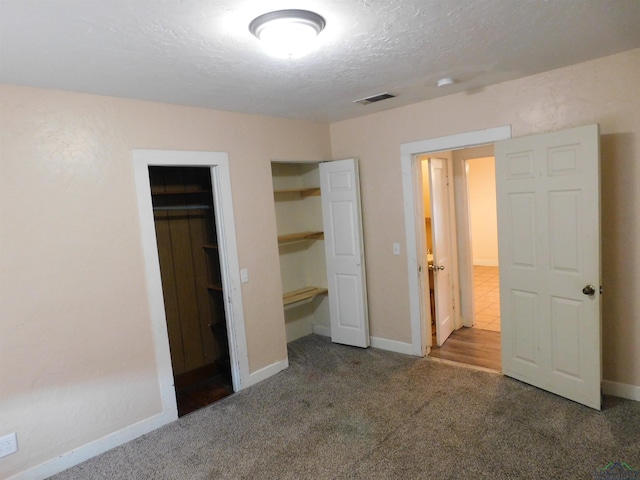 unfurnished bedroom with carpet, a walk in closet, and a closet