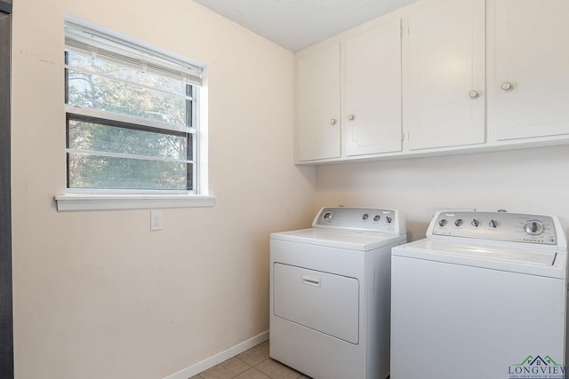 clothes washing area with washer and dryer, cabinets, and light tile patterned floors