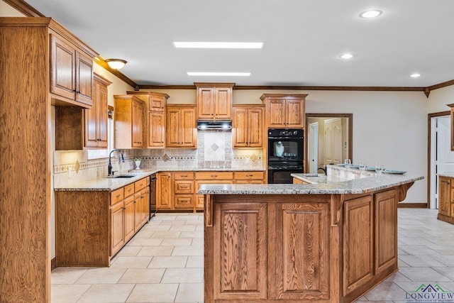 kitchen featuring under cabinet range hood, ornamental molding, decorative backsplash, black appliances, and a sink