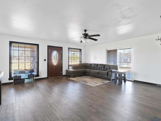 unfurnished living room featuring ceiling fan, a wealth of natural light, and dark hardwood / wood-style floors