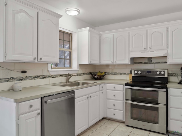 kitchen featuring light tile patterned floors, white cabinetry, appliances with stainless steel finishes, decorative backsplash, and sink