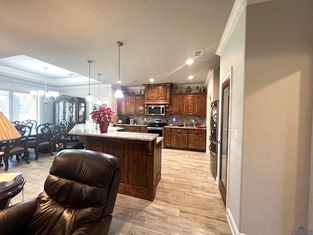 kitchen with appliances with stainless steel finishes, crown molding, decorative light fixtures, a notable chandelier, and a kitchen island