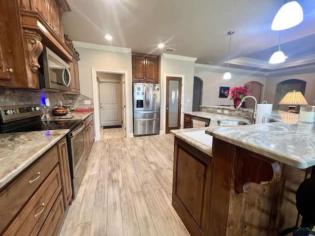 kitchen featuring light wood-type flooring, ornamental molding, stainless steel appliances, sink, and decorative light fixtures