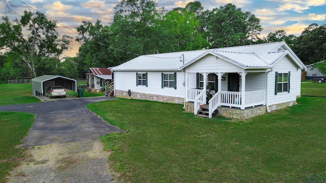 view of front of home with covered porch, a carport, and a lawn