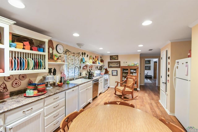 kitchen featuring light stone countertops, sink, stainless steel appliances, white cabinets, and light wood-type flooring