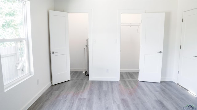 unfurnished bedroom featuring a closet, a spacious closet, and light hardwood / wood-style flooring